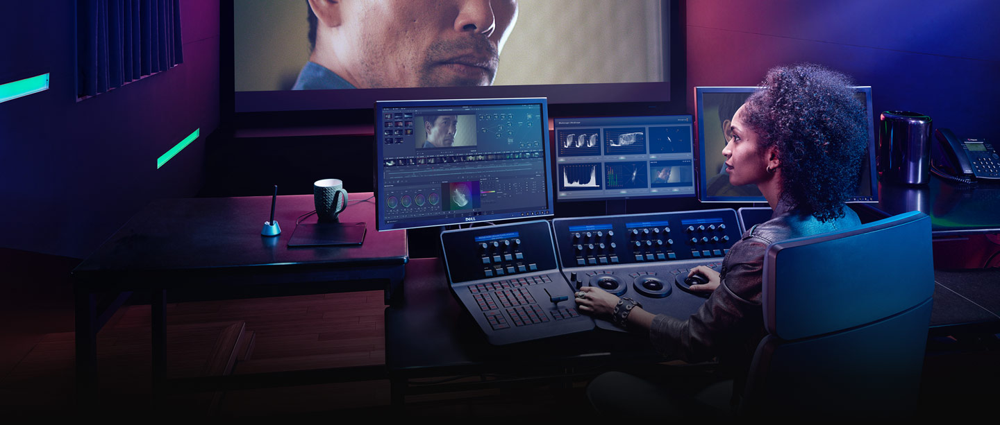 Colorist grading with DaVinci Resolve panels in a purple-lit suite